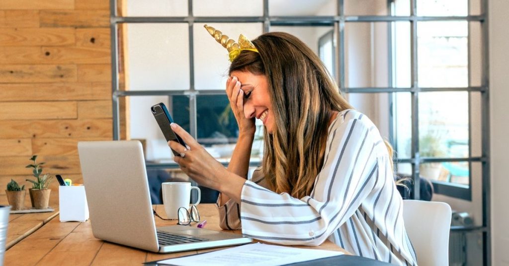 Funny Unicorn Pictures - Business Woman with a Unicorn Horn Laughing While Holding Her Phone